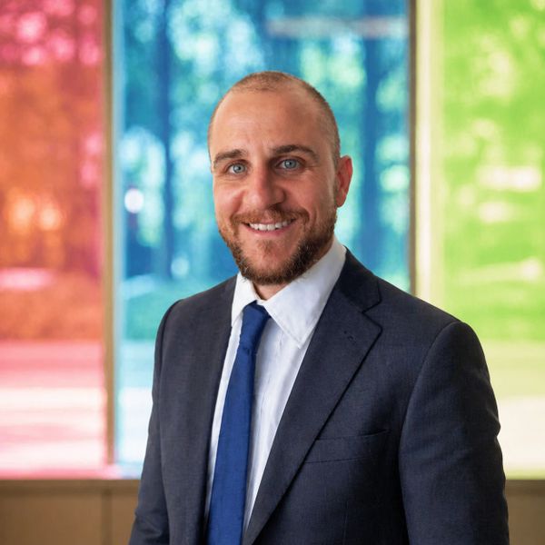 Smiling man in a suit with colorful background panels.