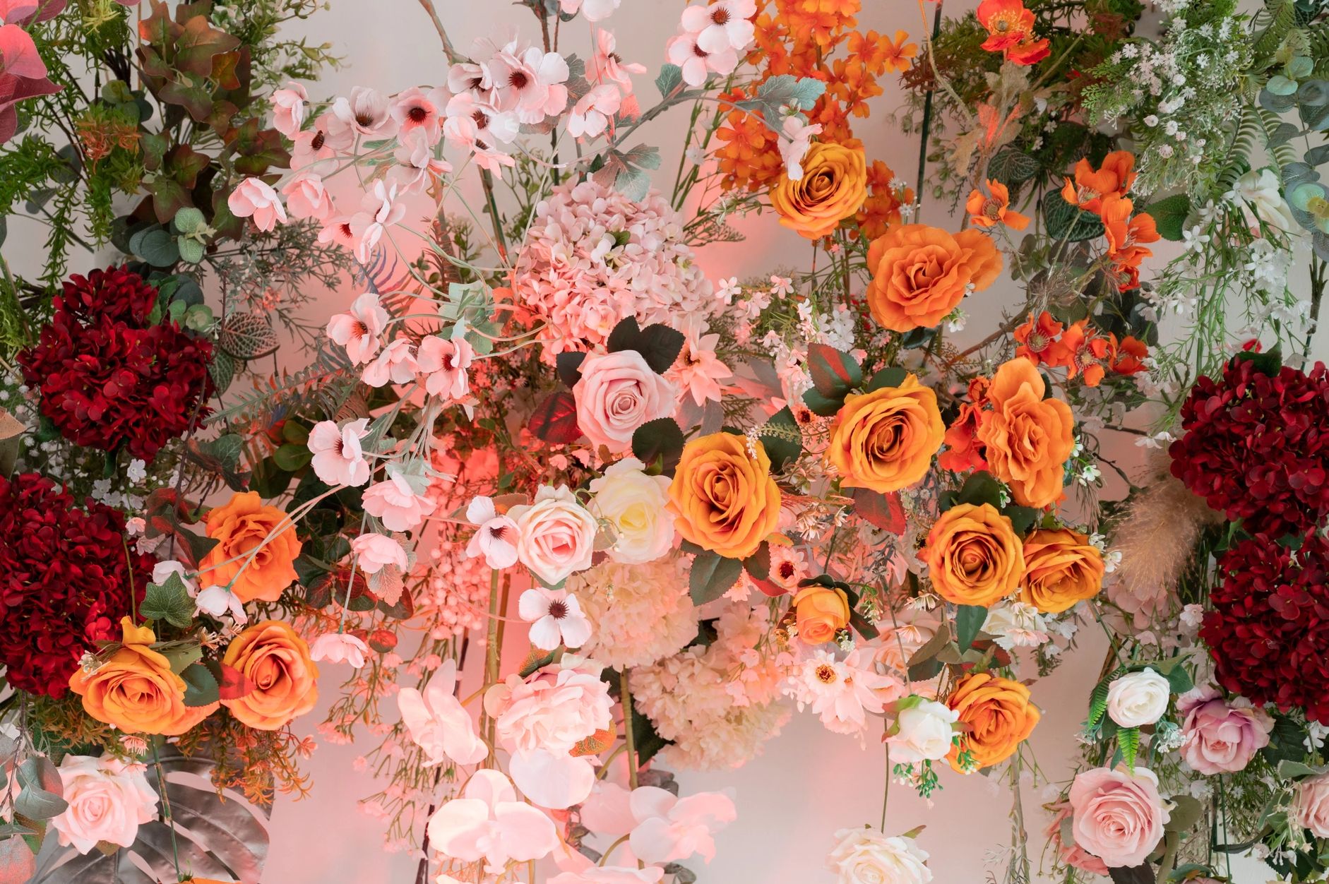 A vibrant floral arrangement with orange, red, and pink flowers accented by silver leaves. Kalamazoo Flower Walls website picture.