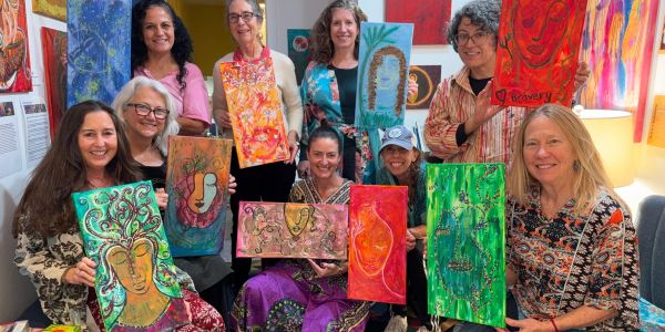 Group of women showing vibrant artwork.
