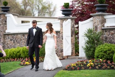 Bride and groom walking hand in hand outdoors.