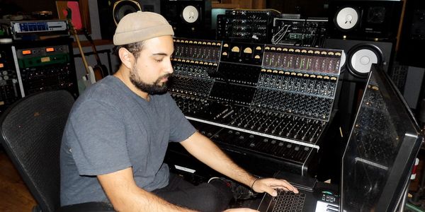 Man working on a laptop in a professional music studio.