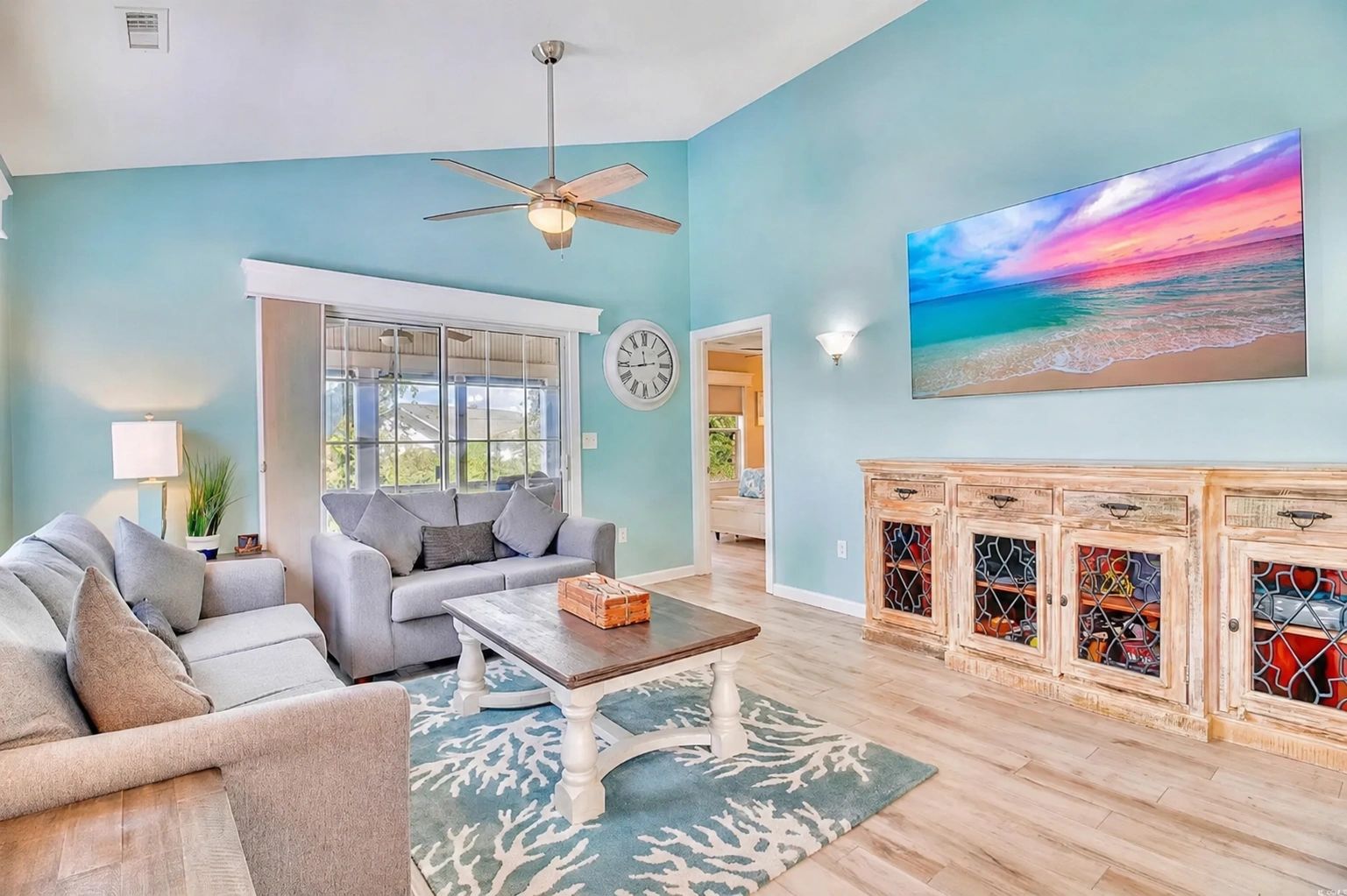 Bright living room with blue walls, gray sofas, and a coastal-themed rug.