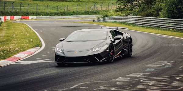 A sleek black Lamborghini sports car driving on a curvy race track.