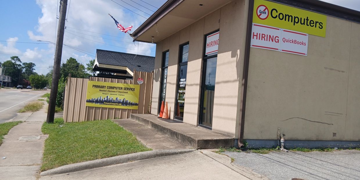 Computer service shop with hiring signs and an American flag.