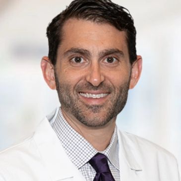 Smiling man in a white coat and tie.