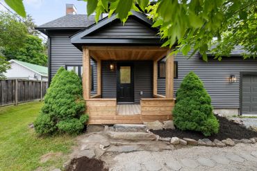 Modern house with black siding and wooden porch.