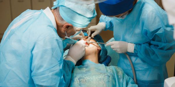 Dentists performing a dental procedure on a patient under anesthesia.