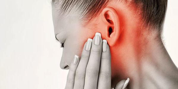 Woman experiencing ear pain, holding her jaw with red inflammation highlighted.