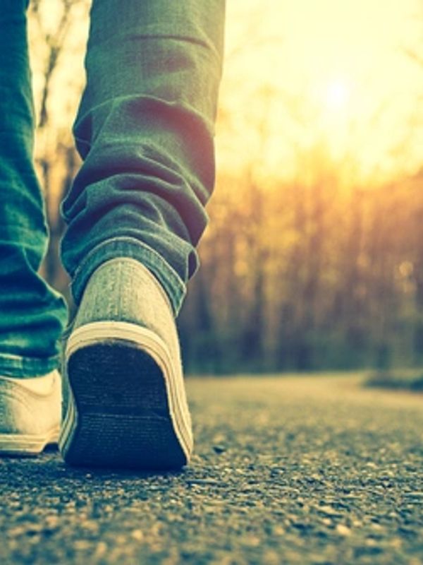 Person walking on a path in sunlight.