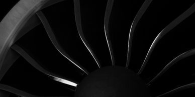 Close-up of jet engine turbine blades in black and white.