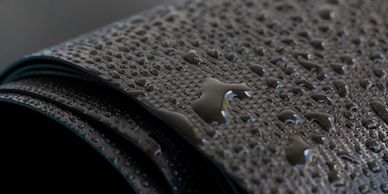 Close-up of water droplets on a textured black surface.