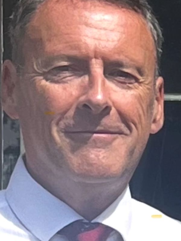 Portrait of a middle-aged man in a white shirt and red tie.