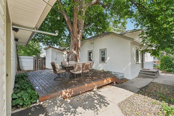 Backyard patio with outdoor dining set under a large tree.