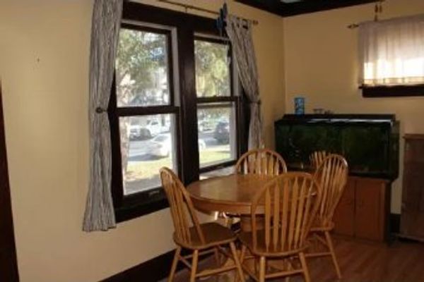 Cozy dining nook with a wooden table and four chairs by a window.