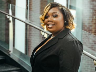 Woman smiling indoors in business attire.