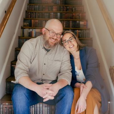 A happy couple sitting closely on the stairs, smiling warmly.