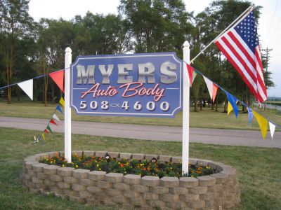 Sign for Myers Auto Body with American flag.