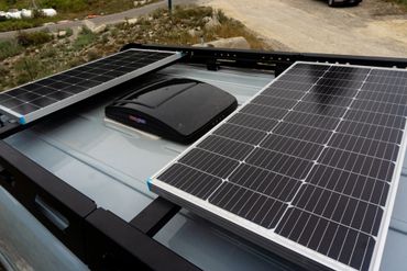 Solar panels and a roof vent mounted on a vehicle roof rack.