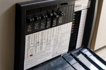 Close-up of an electrical breaker panel with labeled switches and safety instructions.