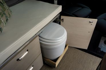 Compact portable toilet neatly stored inside a pull-out cabinet.