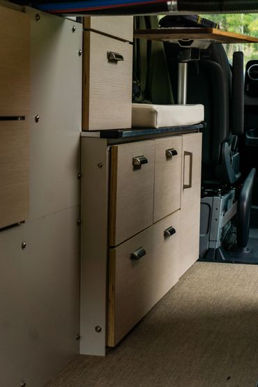 Compact wooden storage cabinets inside a camper van.