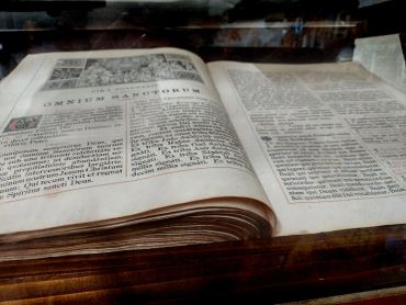 An open antique book with aged pages on a wooden surface.