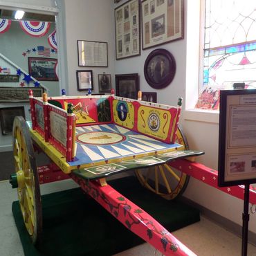 Colorful decorated wooden cart in a museum room.