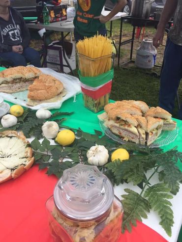 Italian-themed table with sandwiches, lemons, garlic, and pasta on green, white, and red cloth.