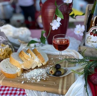 Sliced bread, olives, and a glass of rose wine on a wooden board.