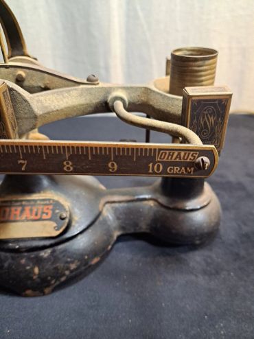 Close-up of a vintage OHAUS gram scale with metal weights.