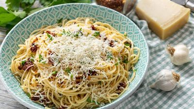 Bowl of spaghetti with grated cheese and herbs.