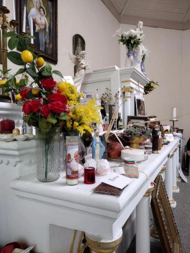 A church altar adorned with flowers, candles, and religious statues.