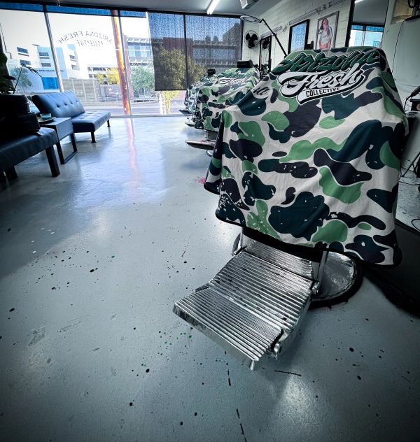 Empty barbershop with camo-patterned chairs and clean floor.