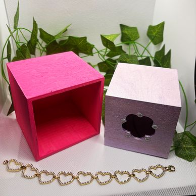 Gold heart-shaped bracelet beside two decorative boxes.
