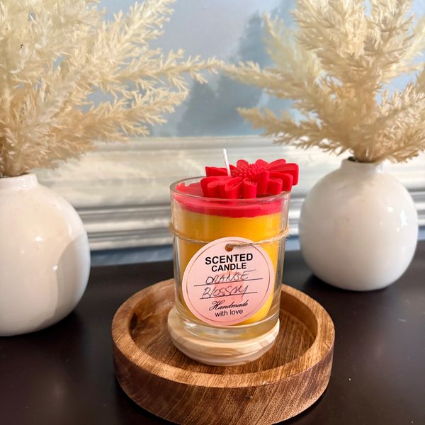 Orange blossom scented candle with decorative red flower top.