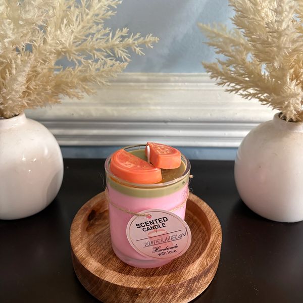 Handmade watermelon scented candle on wooden tray with decorative vases.