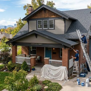 Two workers painting the exterior of a charming two-story house.