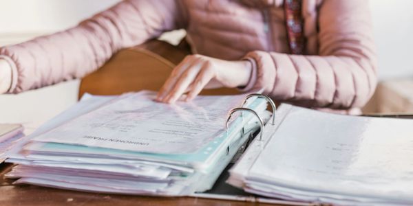 Person organizing documents in a binder at a desk.