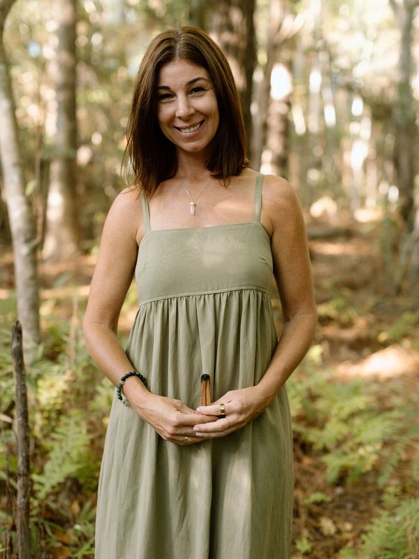 A woman business owner stands among trees with Palo Santo, symbolizing mindful leadership.