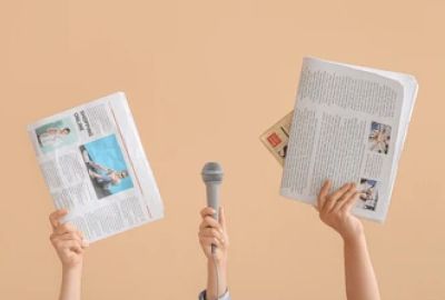 Hands holding newspapers and a microphone.
