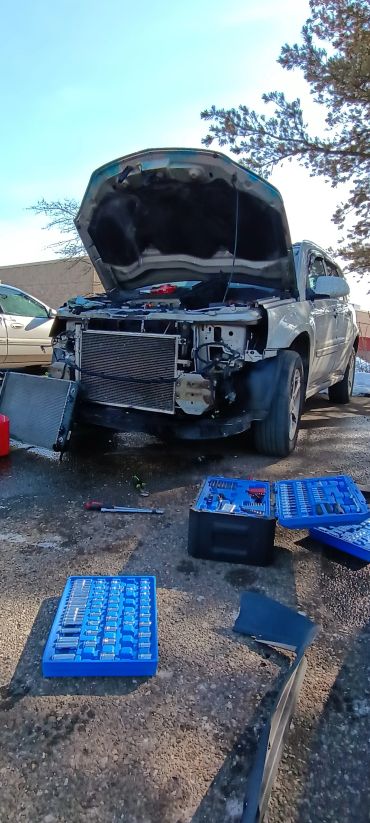 White car with front hood open in repair.