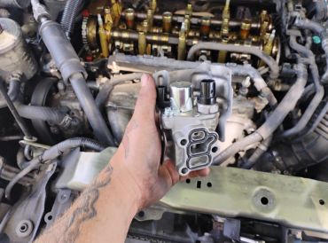 A hand holding a car engine part.
