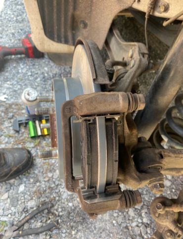 Close-up of car brake caliper and rotor with new brake pads installed.