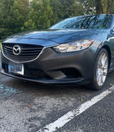 Front view of a gray Mazda car parked outdoors.