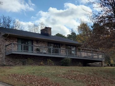 A brick house with a large wooden deck surrounded by trees in autumn.