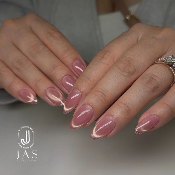 Nude pink nails with a subtle glittery French tip design.
