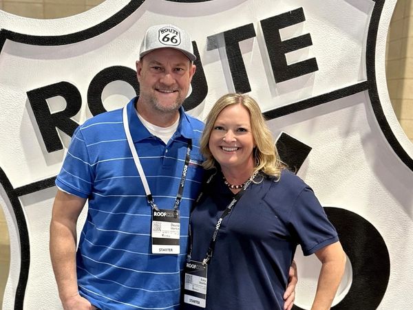 A smiling couple poses in front of a large Route 66 sign at an event.
