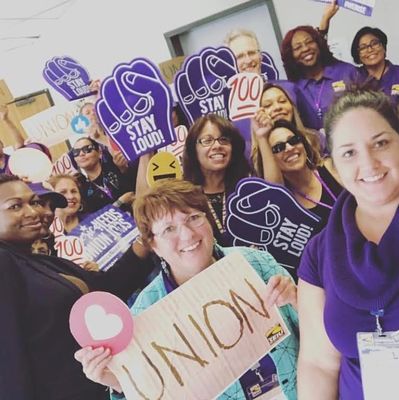 A group of diverse people holding union signs and smiling for a selfie.