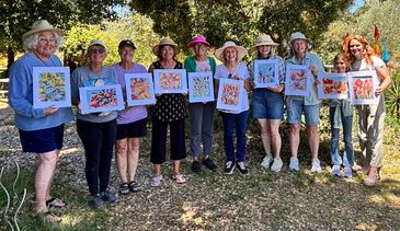 Group holding colorful artwork outdoors.