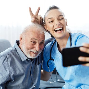 Older man and nurse taking a playful selfie.